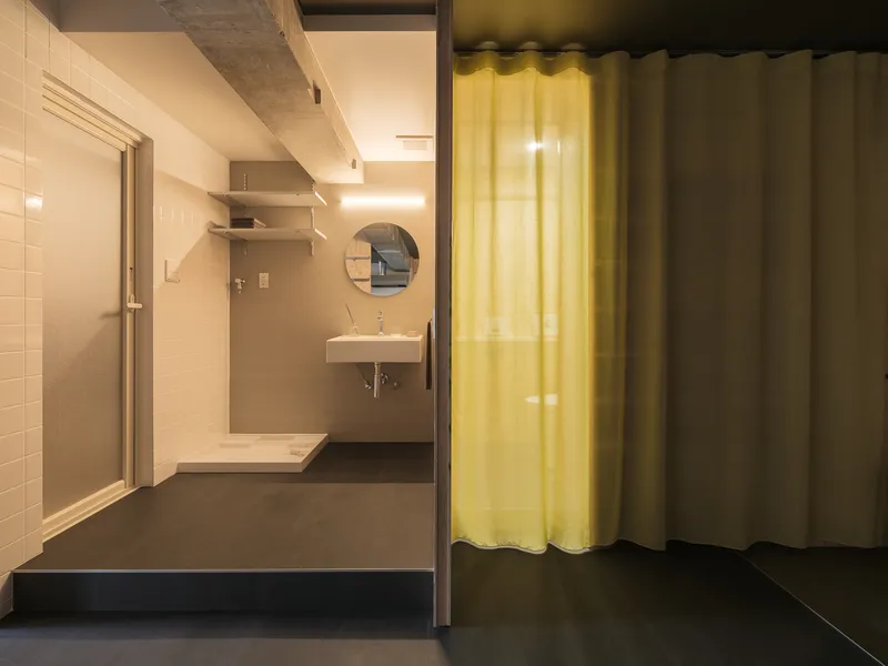 Bathroom with yellow curtain divider, wall-mounted sink, and exposed concrete ceiling beam