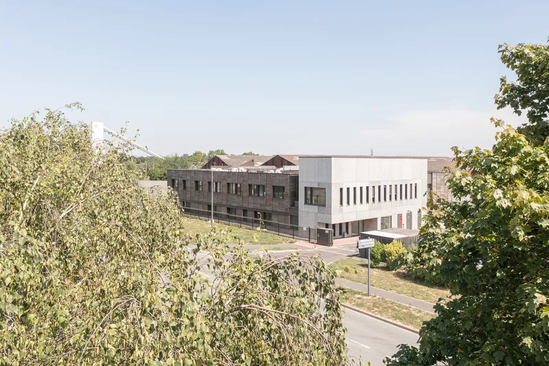 Elevated view of the two-story building complex framed by deciduous trees in late summer light