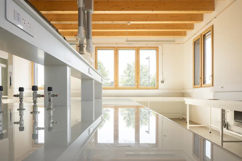Light-filled laboratory with polished epoxy flooring, exposed timber beams, and triple casement windows