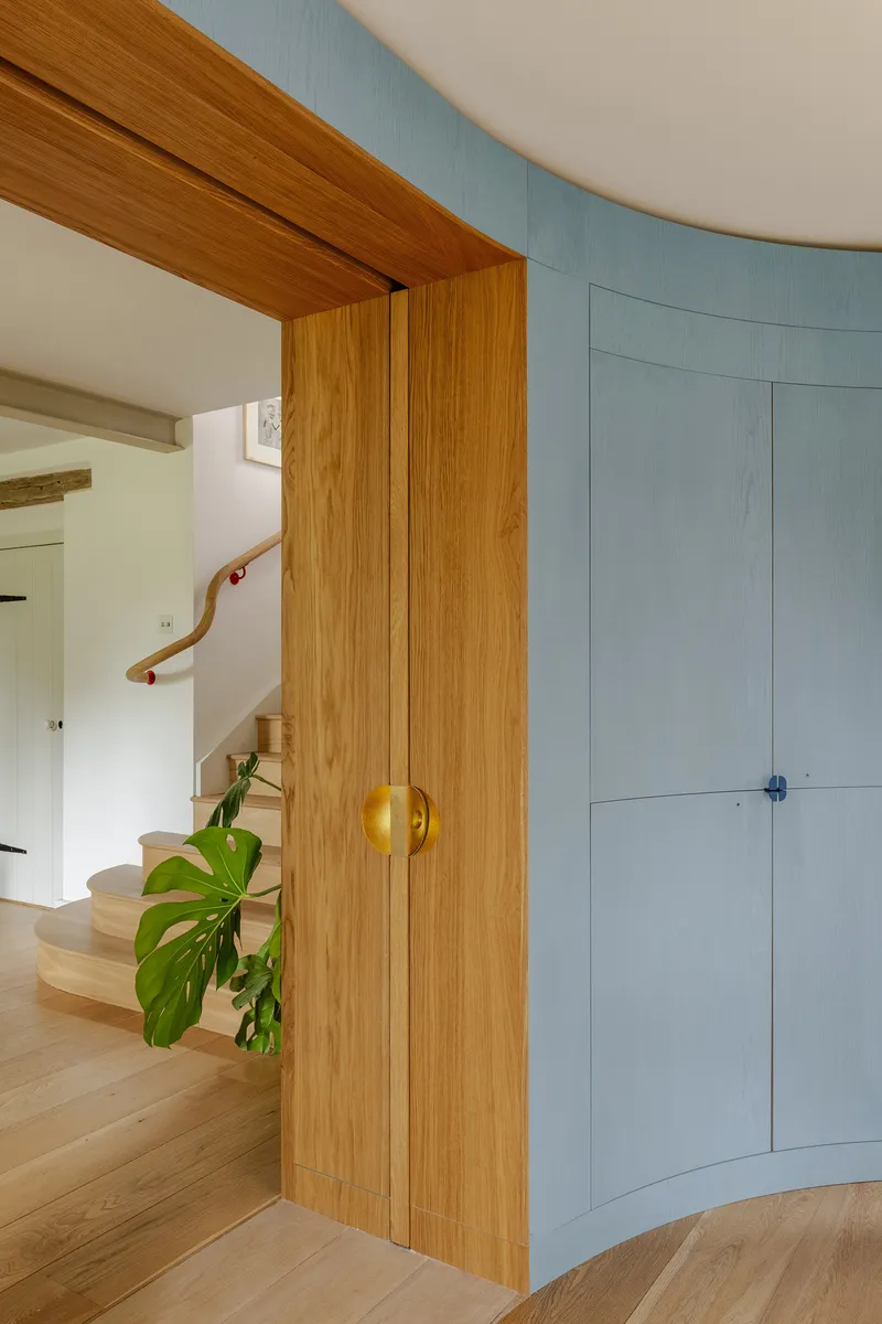 Timber door with spherical brass handle opening to staircase with curved wall and handrail beyond