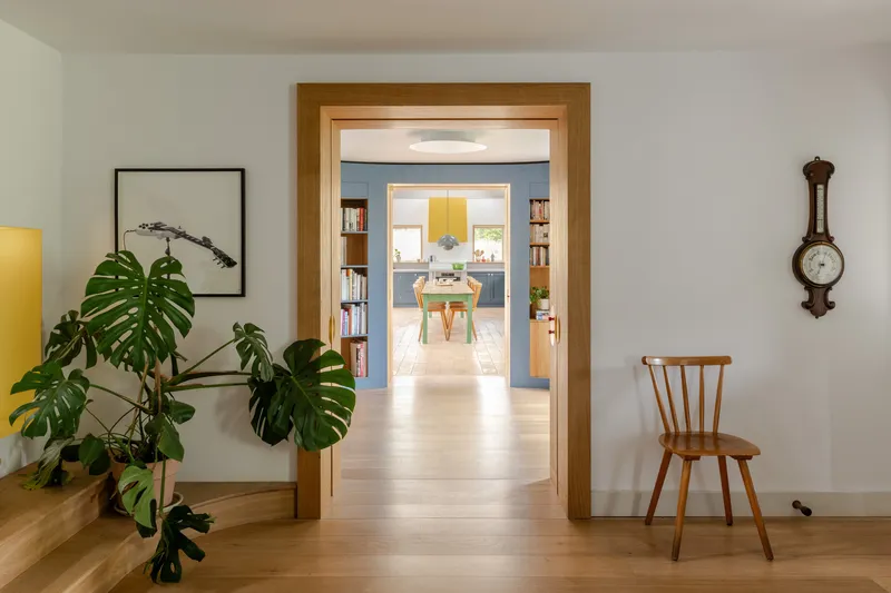 Oak-framed doorway leading through aligned rooms with monstera plant and antique barometer on wall