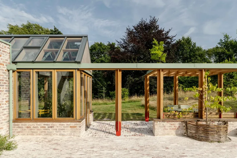 Covered terrace with exposed timber columns and beams extending from a glazed brick pavilion