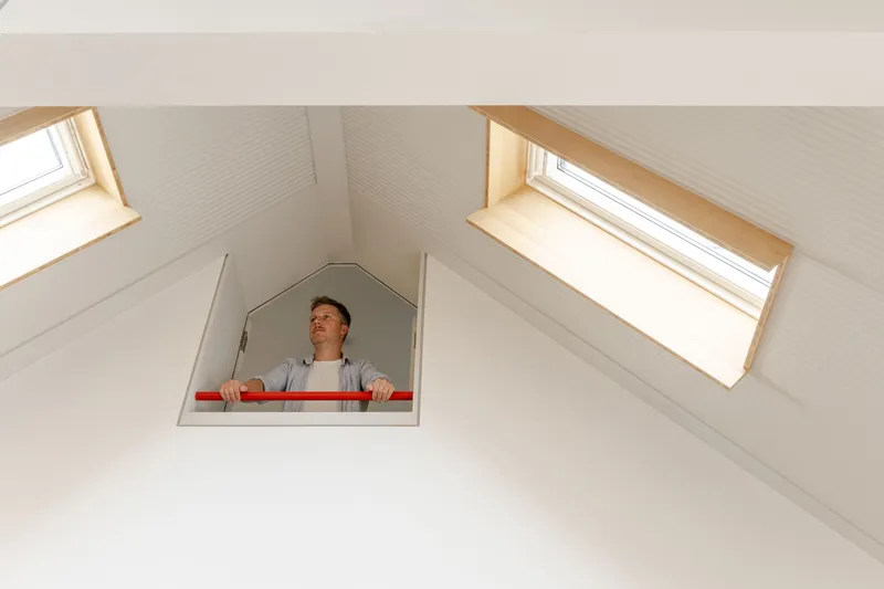 Person looking down through pentagonal hatch in vaulted ceiling with two skylights