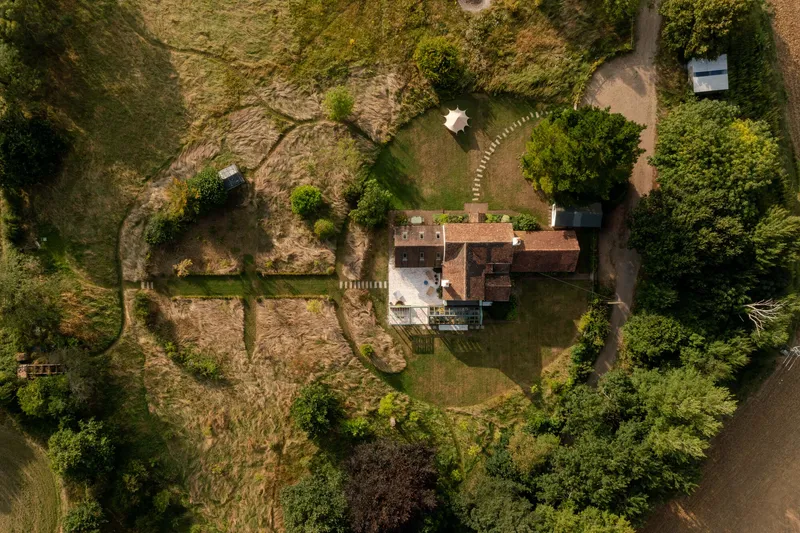 Aerial view of the house and its terracotta roof surrounded by gardens and deciduous trees
