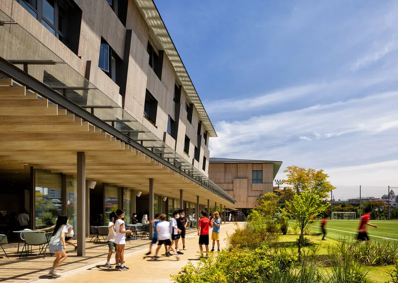 Open terrace with timber canopy and external glass staircase leading to playing fields beyond