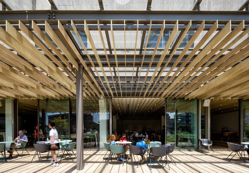 Slatted timber pergola casting shadow patterns over an outdoor dining terrace with seated figures