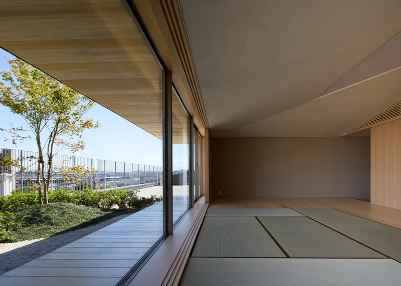 Tatami room with sliding glass doors opening onto a timber deck and planted terrace
