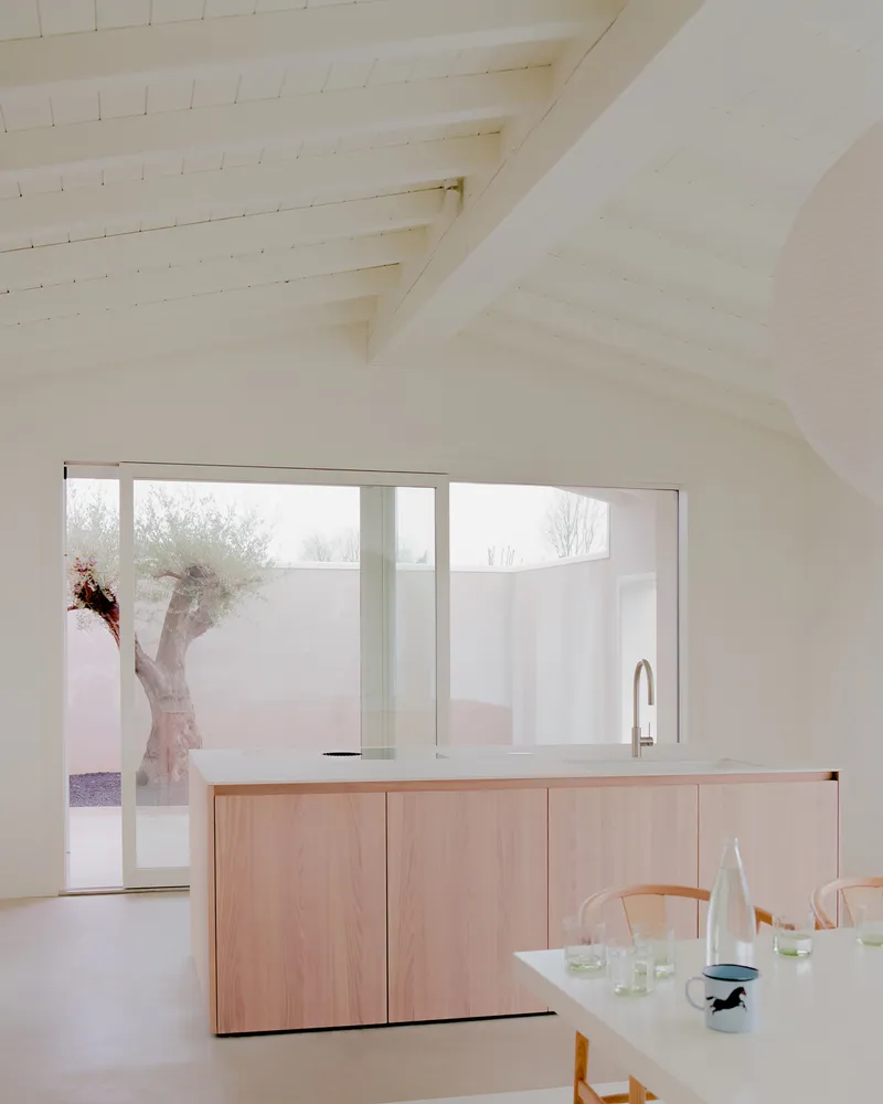 Open kitchen with light timber cabinetry beneath a vaulted ceiling with exposed timber beams and planks