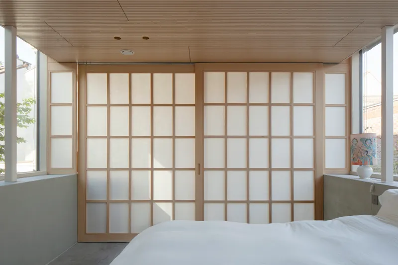 Closed shoji screen wall with timber grid frames and translucent panels in afternoon light
