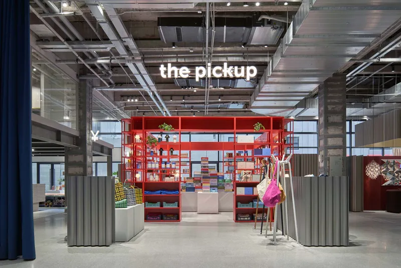 Red metal shelving unit with corrugated metal screens beneath exposed concrete ceiling and visible mechanical systems