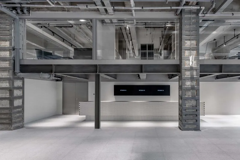 Interior view of double-height space with exposed concrete columns, steel beams, and central service counter