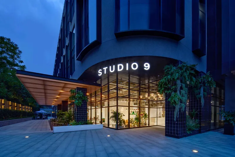 Entrance canopy with glazed corner facade and vertical tile-clad columns at dusk