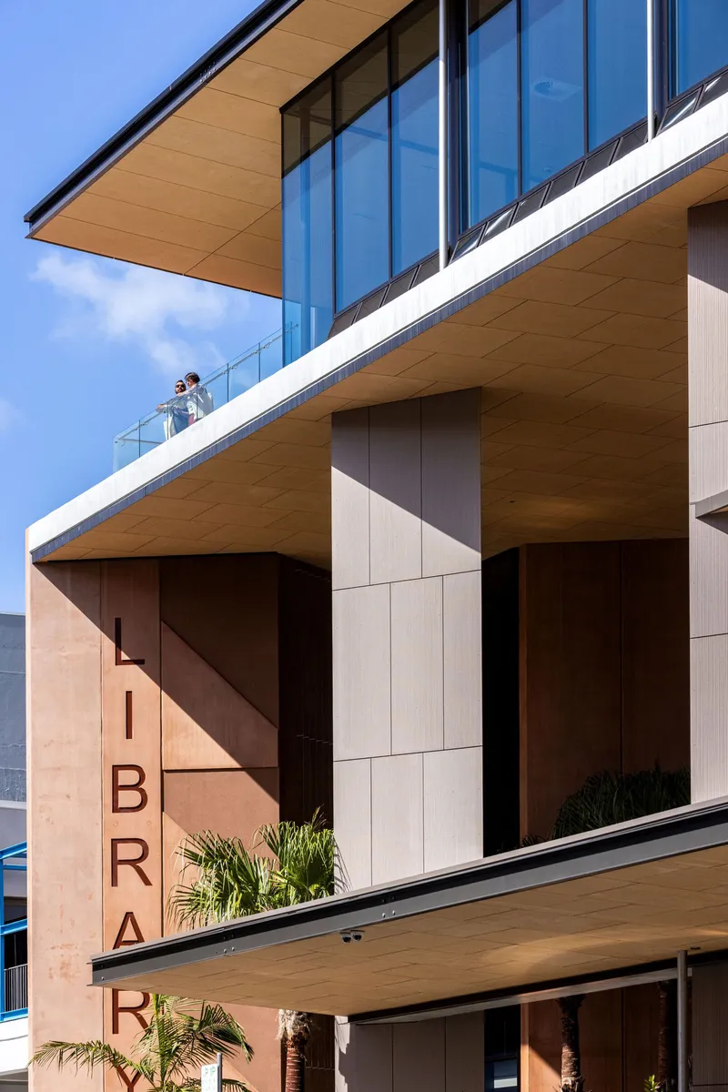 Detail of stacked terraces with timber cladding and planted palms on a clear day