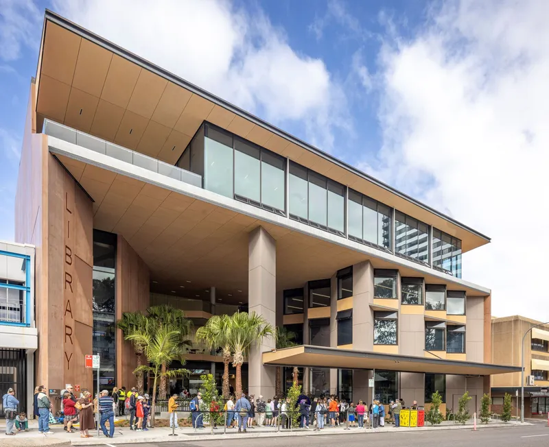 Entrance elevation with gathering crowd beneath deep canopy supported by cylindrical columns