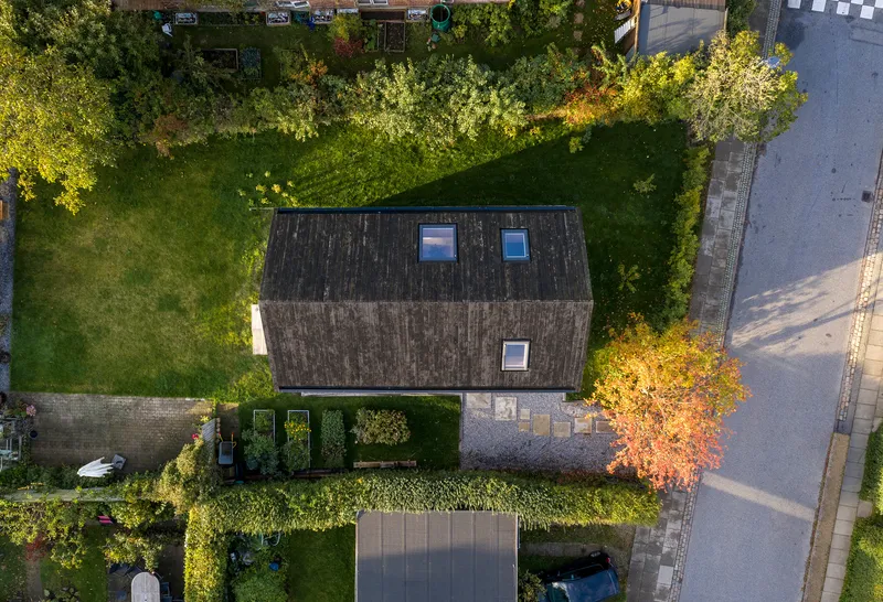 Overhead view of the vertical-clad pitched roof with three skylights surrounded by garden and driveway