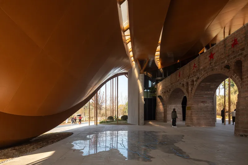 Interior courtyard framed by curving timber ceiling and brick arches with visitors walking through