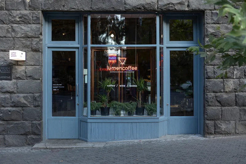 Blue-painted timber storefront with bay window and potted plants against grey stone facade