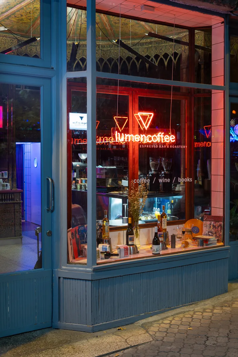 Blue-framed shopfront window with neon signage and display counter at dusk