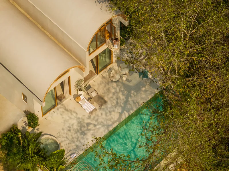 Aerial view of the terrace with swimming pool and arched openings surrounded by tropical vegetation