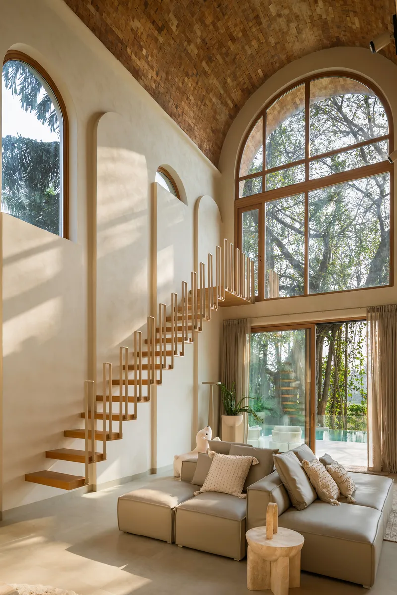 Living space beneath the vaulted brick ceiling showing the cantilevered staircase and full-height glazed openings