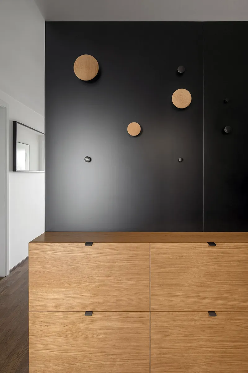 Sculptural black wall with oak accents as a graphic focal point