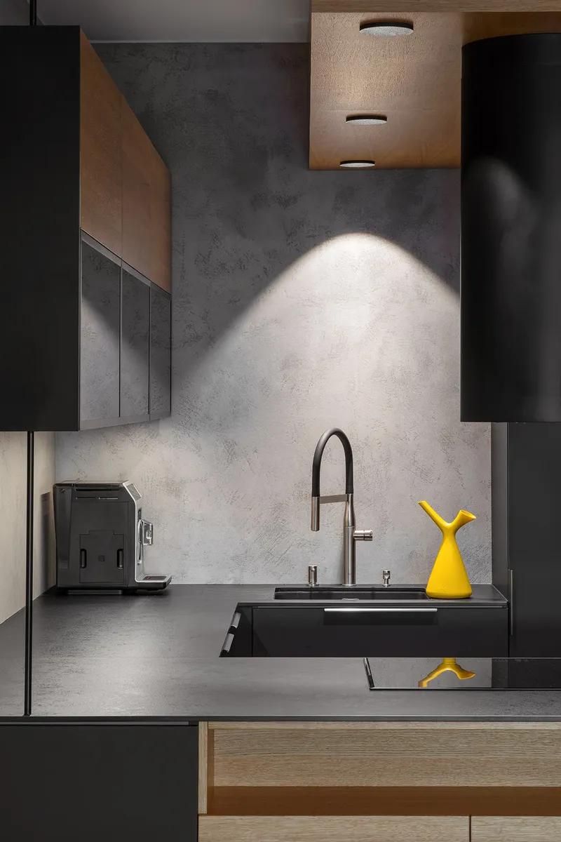 Minimal black kitchen with oak detailing and a bold mustard accent