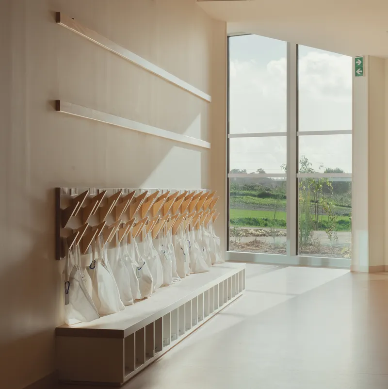Corridor with wooden coat rack and floating shelves beneath tall window overlooking landscape