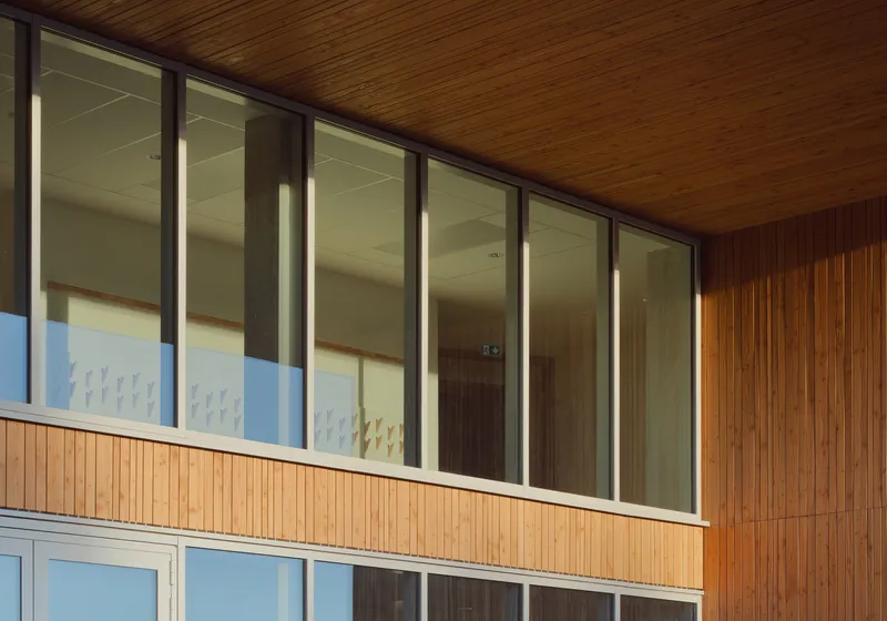 Exterior facade with vertical timber cladding and ribbon windows beneath soffit overhang
