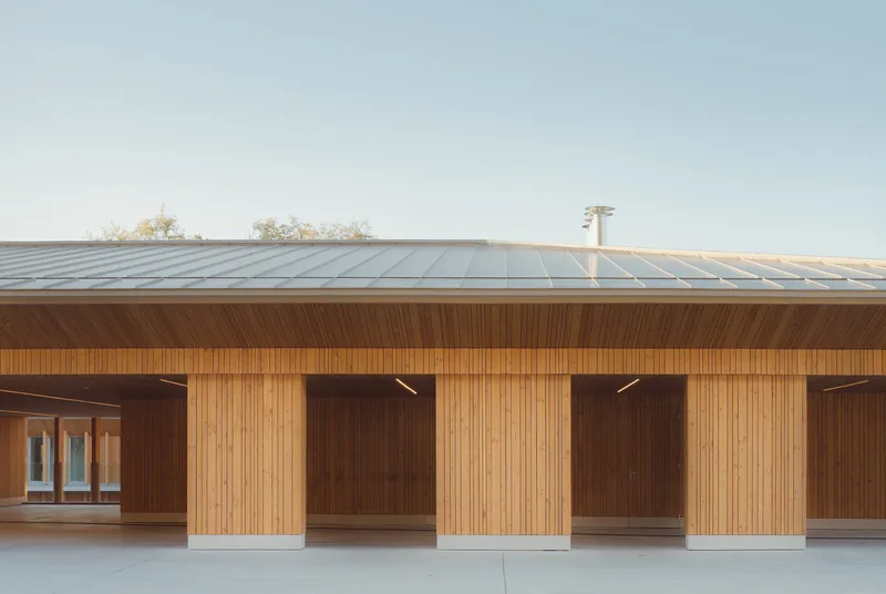 Covered walkway with vertical timber cladding and recessed bays beneath a standing seam metal roof