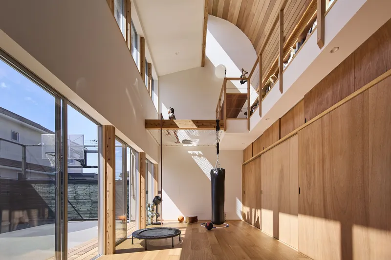 Double-height interior space with timber-framed walls and clerestory windows casting sunlight across the wood floor