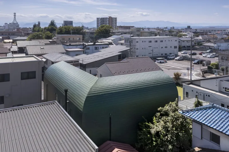 Aerial view of the curved corrugated metal roof rising above the surrounding residential neighborhood