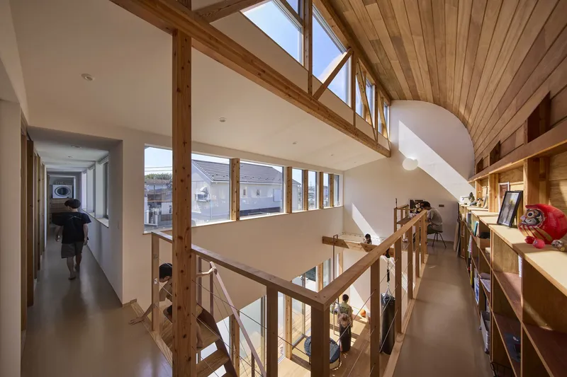 Double-height space with exposed timber frame, clerestory windows and a wooden staircase connecting upper and lower levels