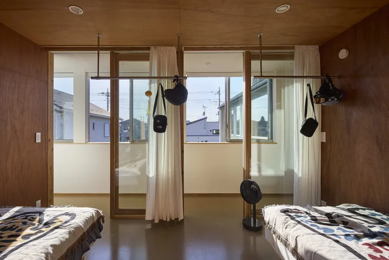 Bedroom with sliding glass doors opening to a balcony and hanging storage bags suspended from ceiling rods