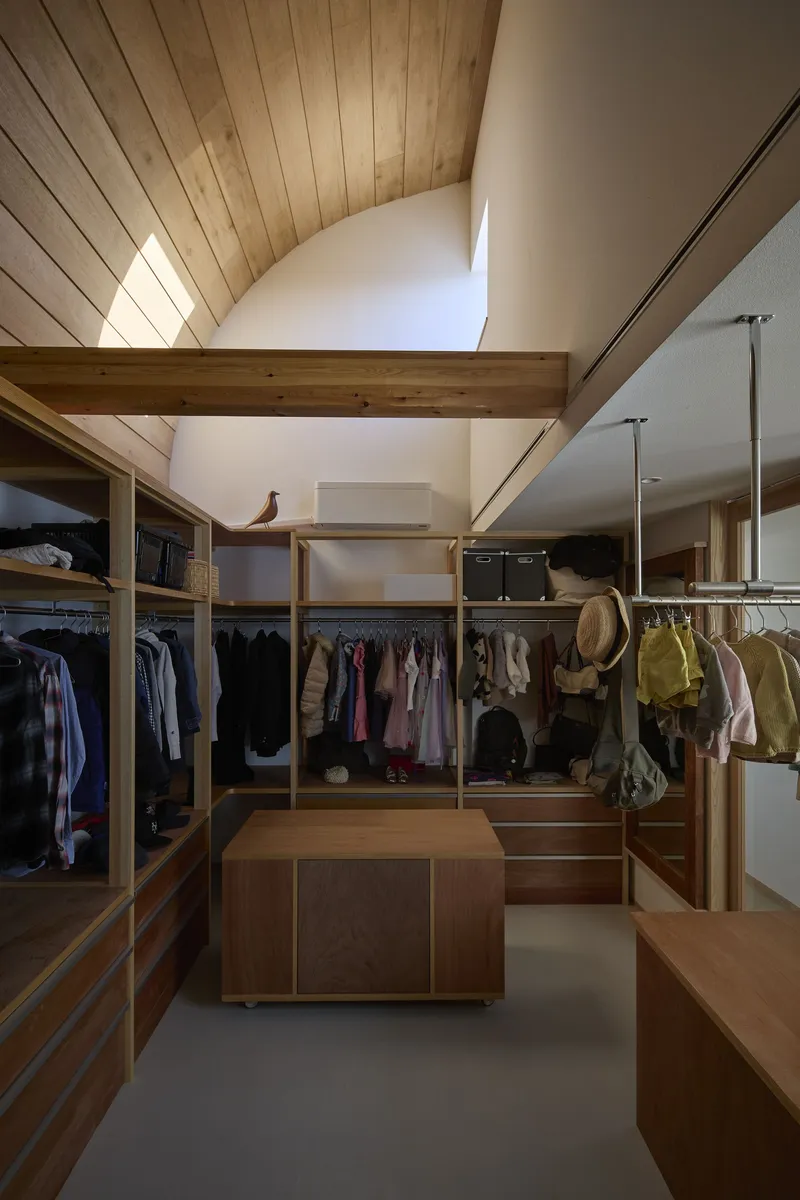 Walk-in closet with timber shelving and central island beneath exposed wood beams and skylight