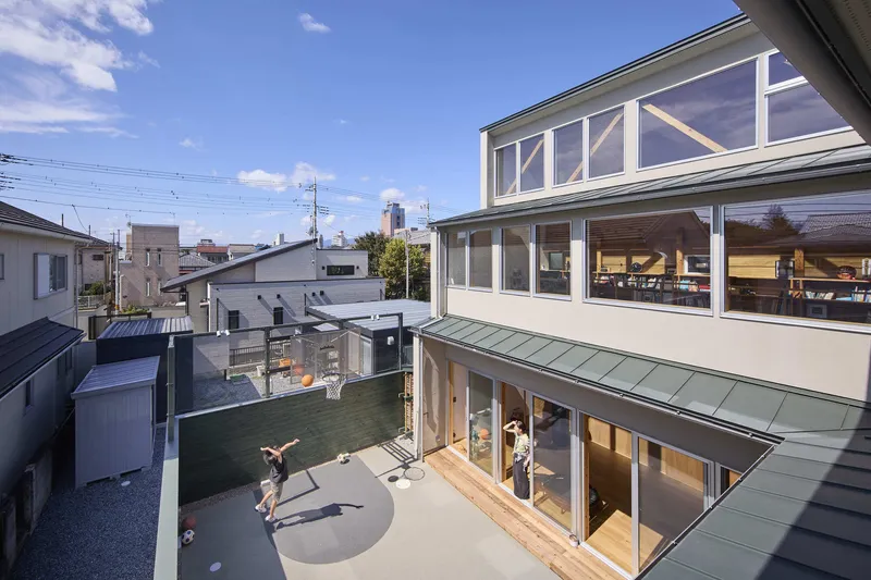 Courtyard view showing stacked volumes with glazed facades and children playing on concrete terrace