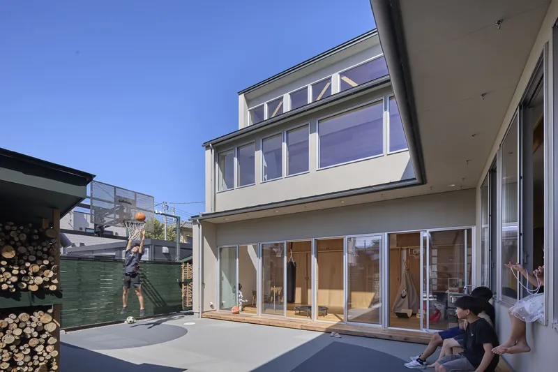 Courtyard facade with sliding glass doors and family gathered on paved terrace at dusk