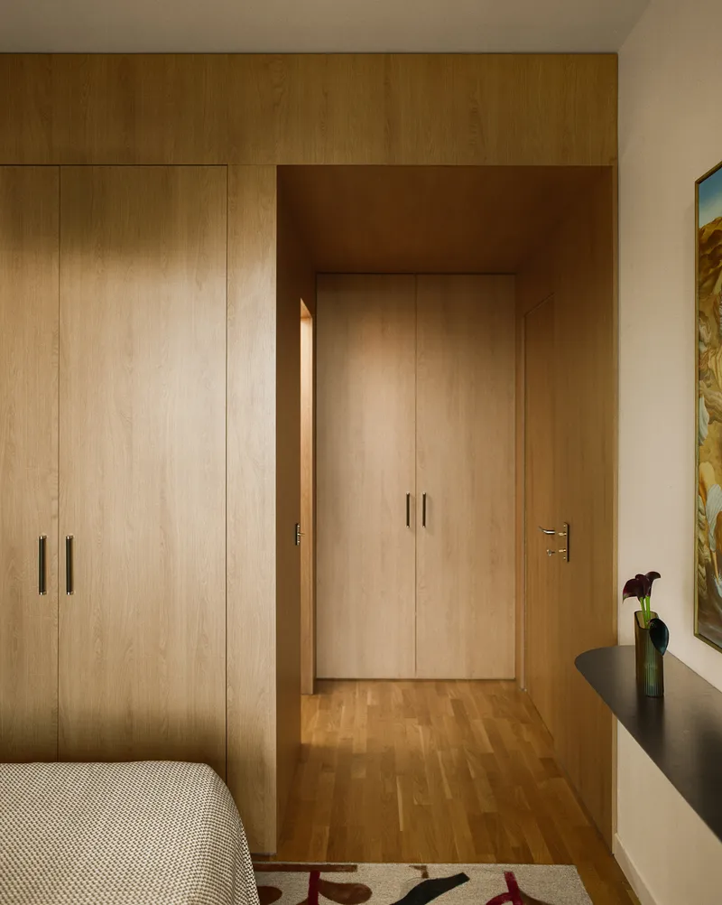 Wood-paneled hallway with built-in wardrobes and oak flooring lit by afternoon sunlight
