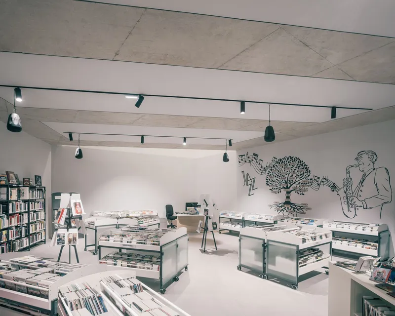 Upper level gallery space with white walls, exposed timber beams and wall mural overlooking display tables