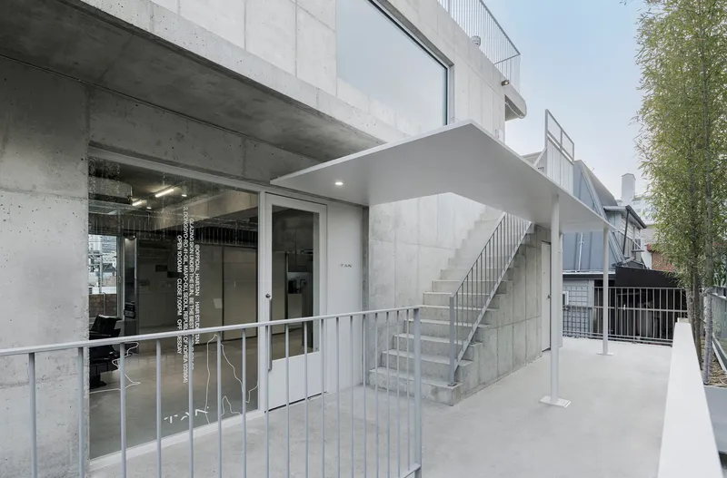 Exterior entrance terrace with metal railings and external stair leading to upper levels in daylight