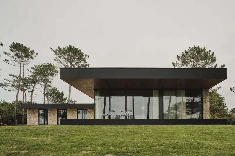 Rear elevation showing the cantilevered roof, full-height glazing and timber soffit facing the lawn