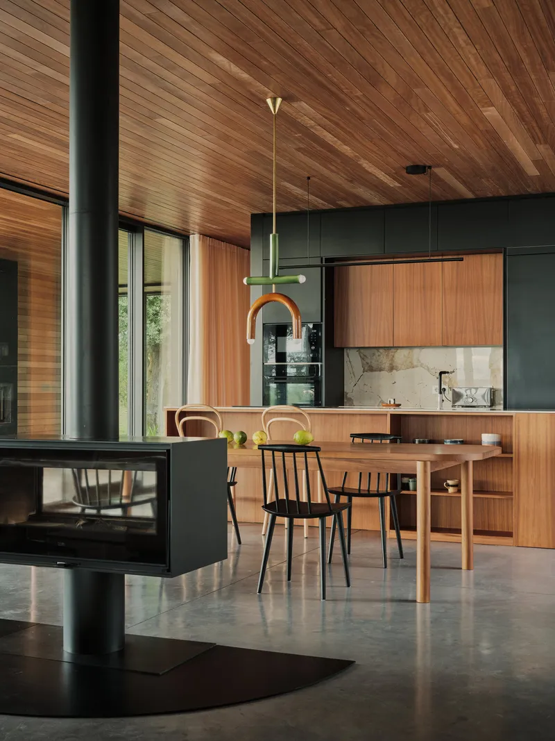 Open-plan kitchen and dining area with freestanding fireplace under timber slat ceiling