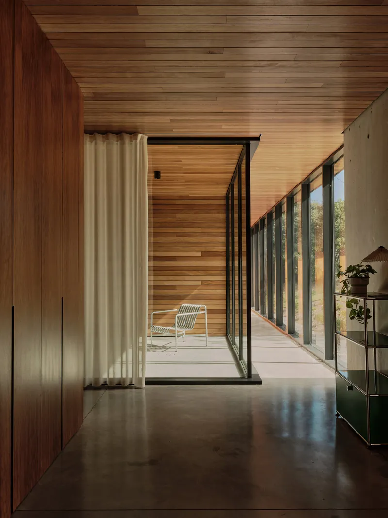 Corridor with timber cladding leading to a glazed door opening onto a private courtyard