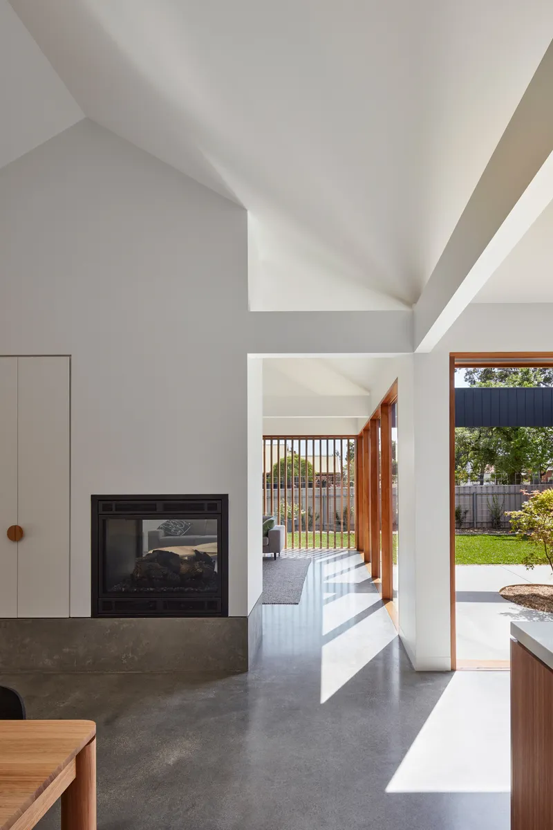 Living room interior with concrete fireplace base looking through to the garden courtyard in afternoon light