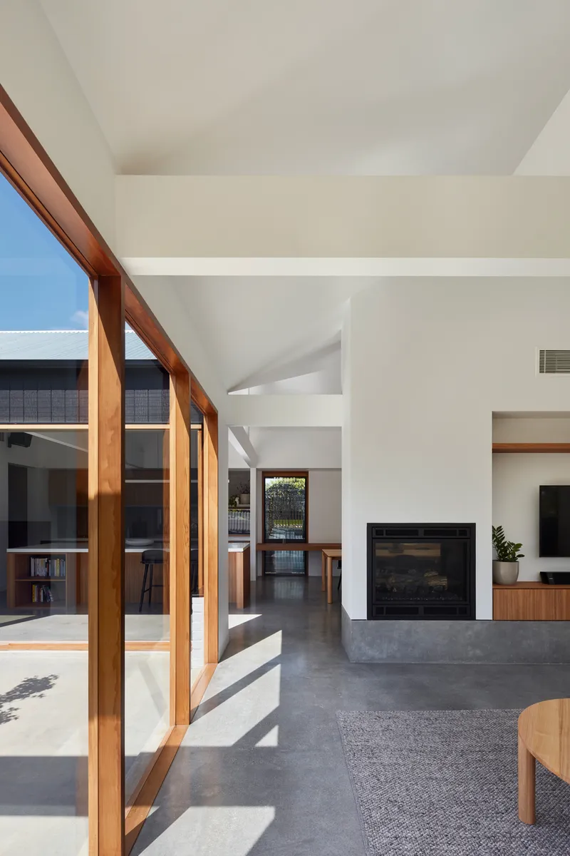 Living area with polished concrete floor and timber framed sliding glass doors opening to the courtyard