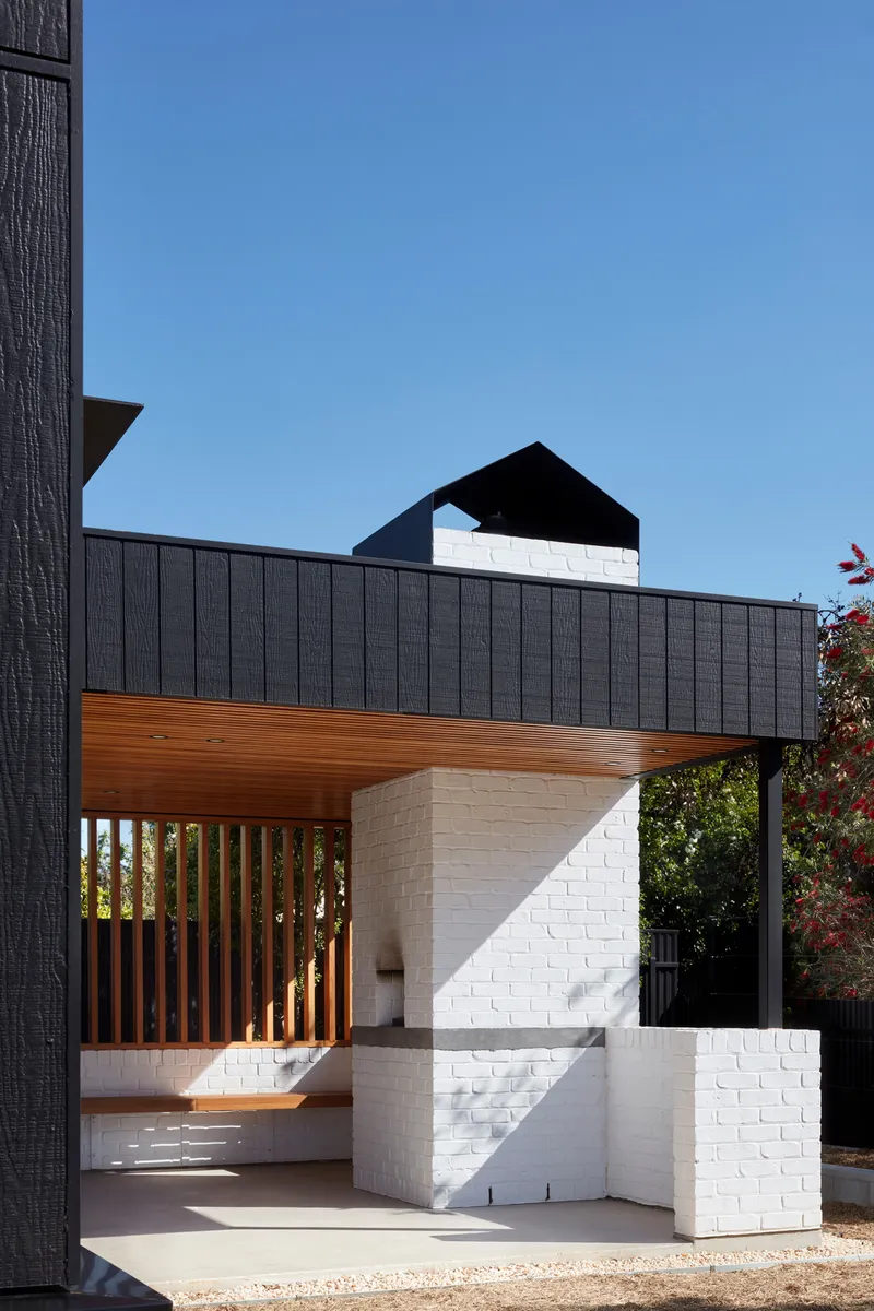 Covered entry porch with timber soffit and white brick stair alongside vertical timber screening