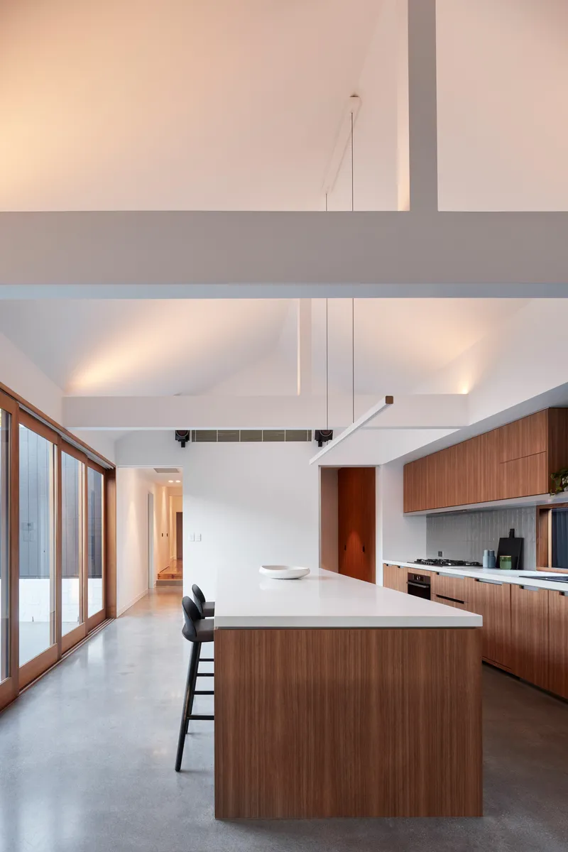 Open plan kitchen and living space with timber joinery and mezzanine level at dusk