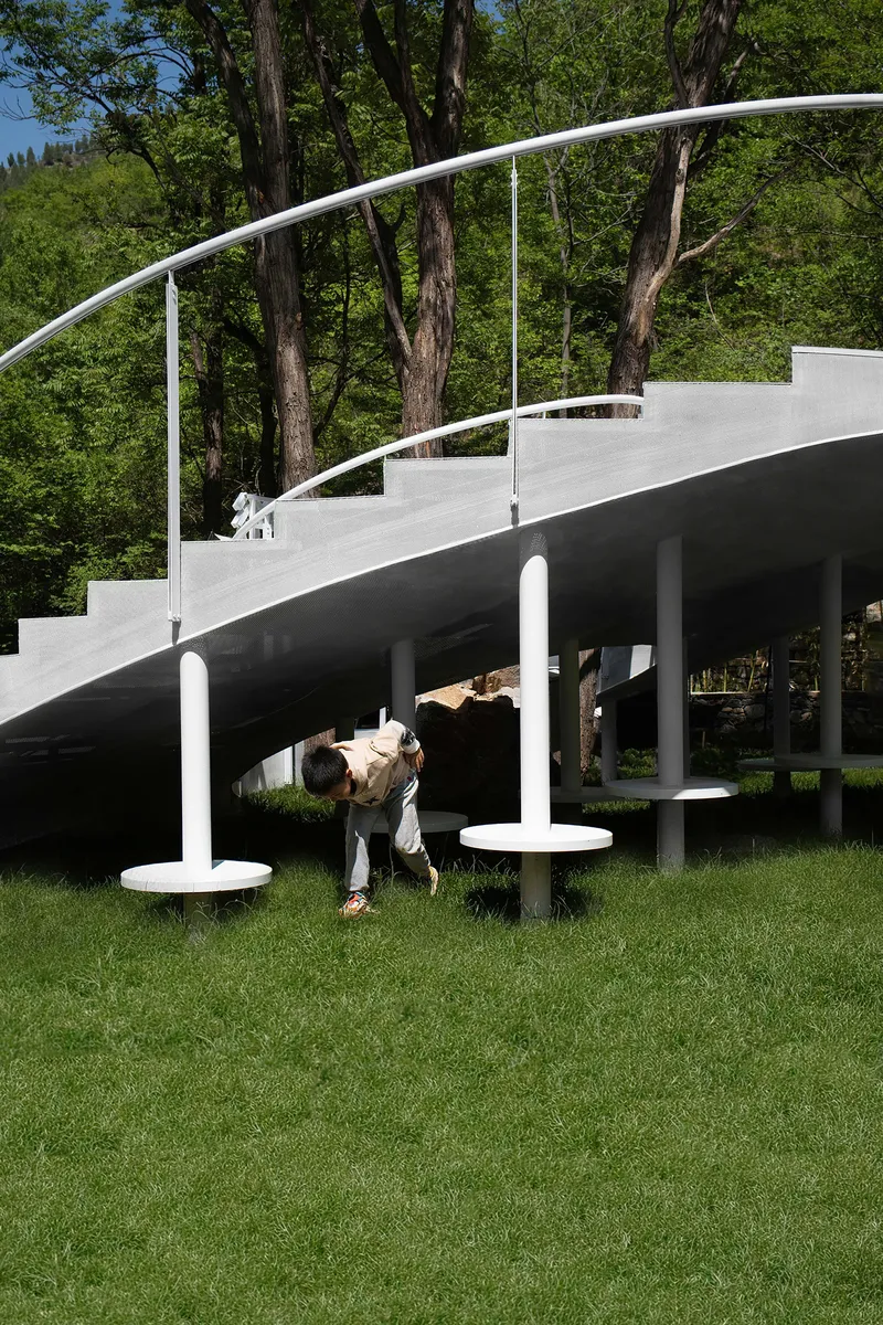 Underside of the curved stair structure with cylindrical columns as a visitor bends down