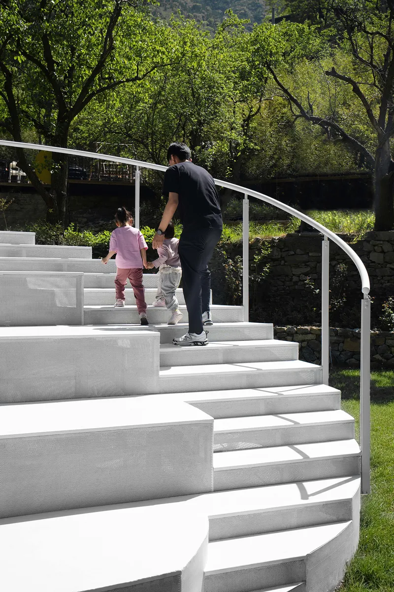 White concrete steps with curved metal handrail as a parent and children ascend