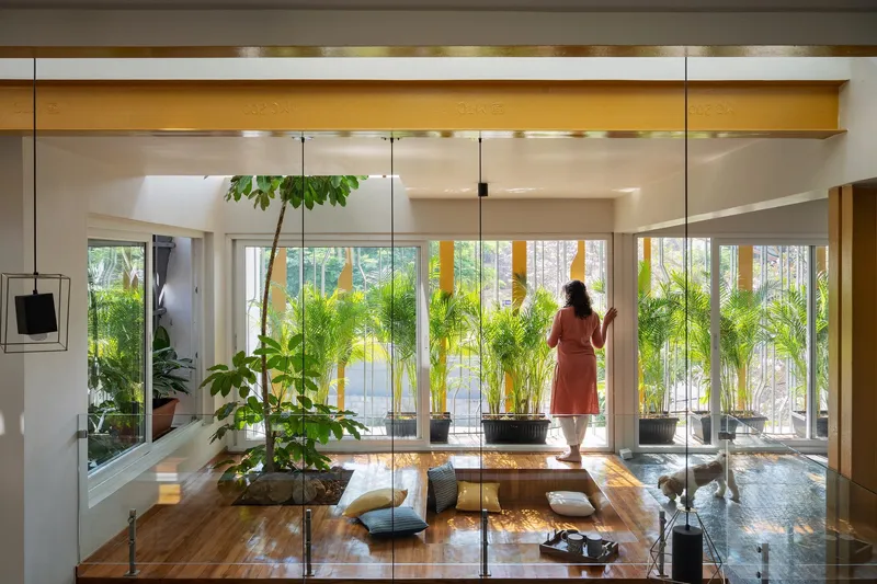 Interior living space with floor-to-ceiling glass doors overlooking a planted courtyard with bamboo