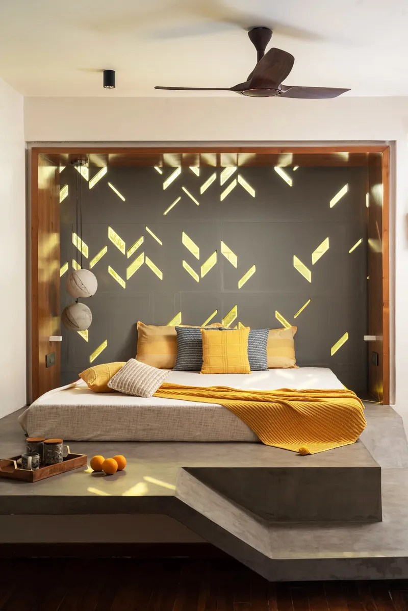 Bedroom alcove framed in timber with a backlit grey wall featuring chevron cutouts casting geometric shadows